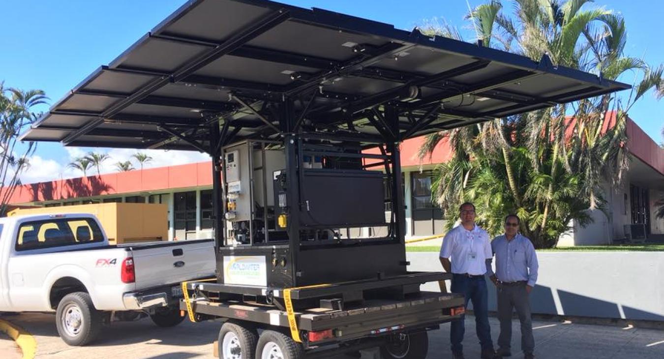 Two people standing next to generator on trailer