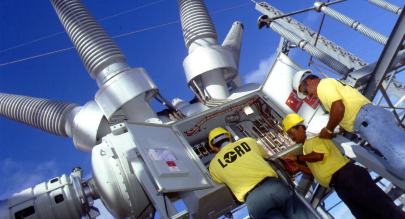 Three electrical workers with industrial transformer