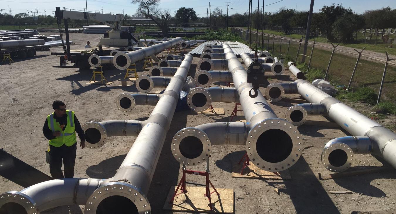 Large outdoor yard where industrial metal piping is being assembled