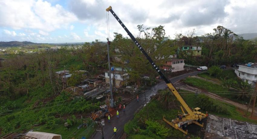 Crane lifting debris on a grassy hill