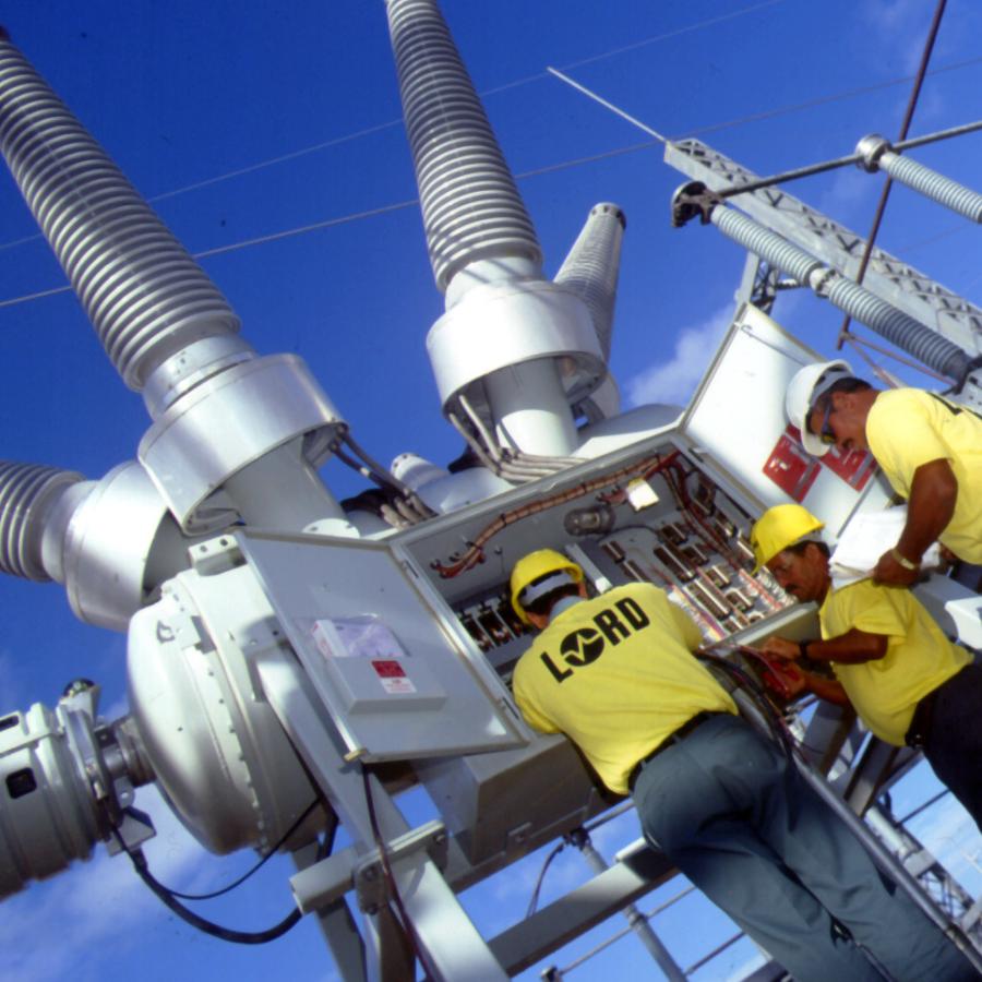 3 Construction employees working in an industrial transformer yard