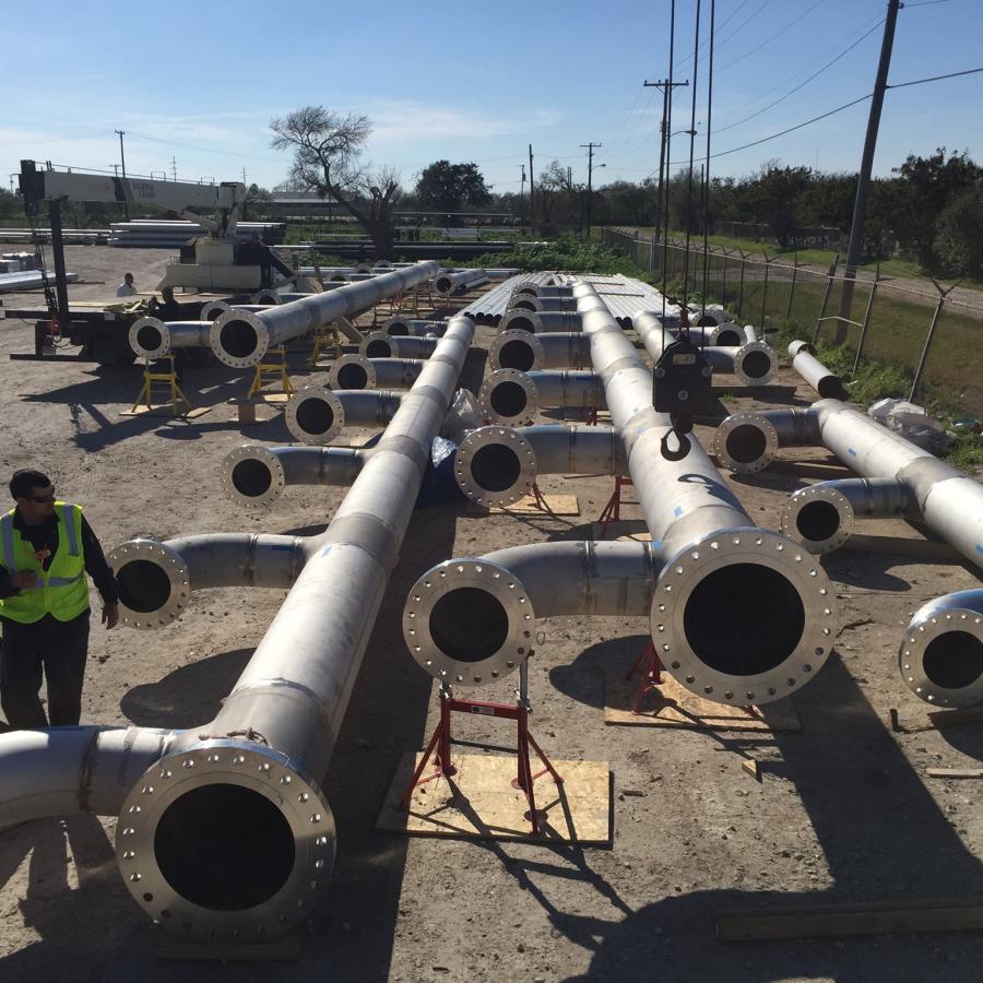 Large outdoor yard where industrial metal piping is being assembled